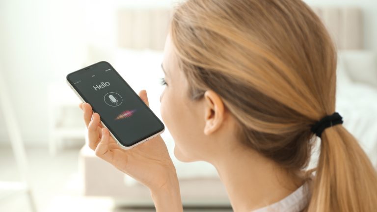 Young woman using voice search on smartphone indoors